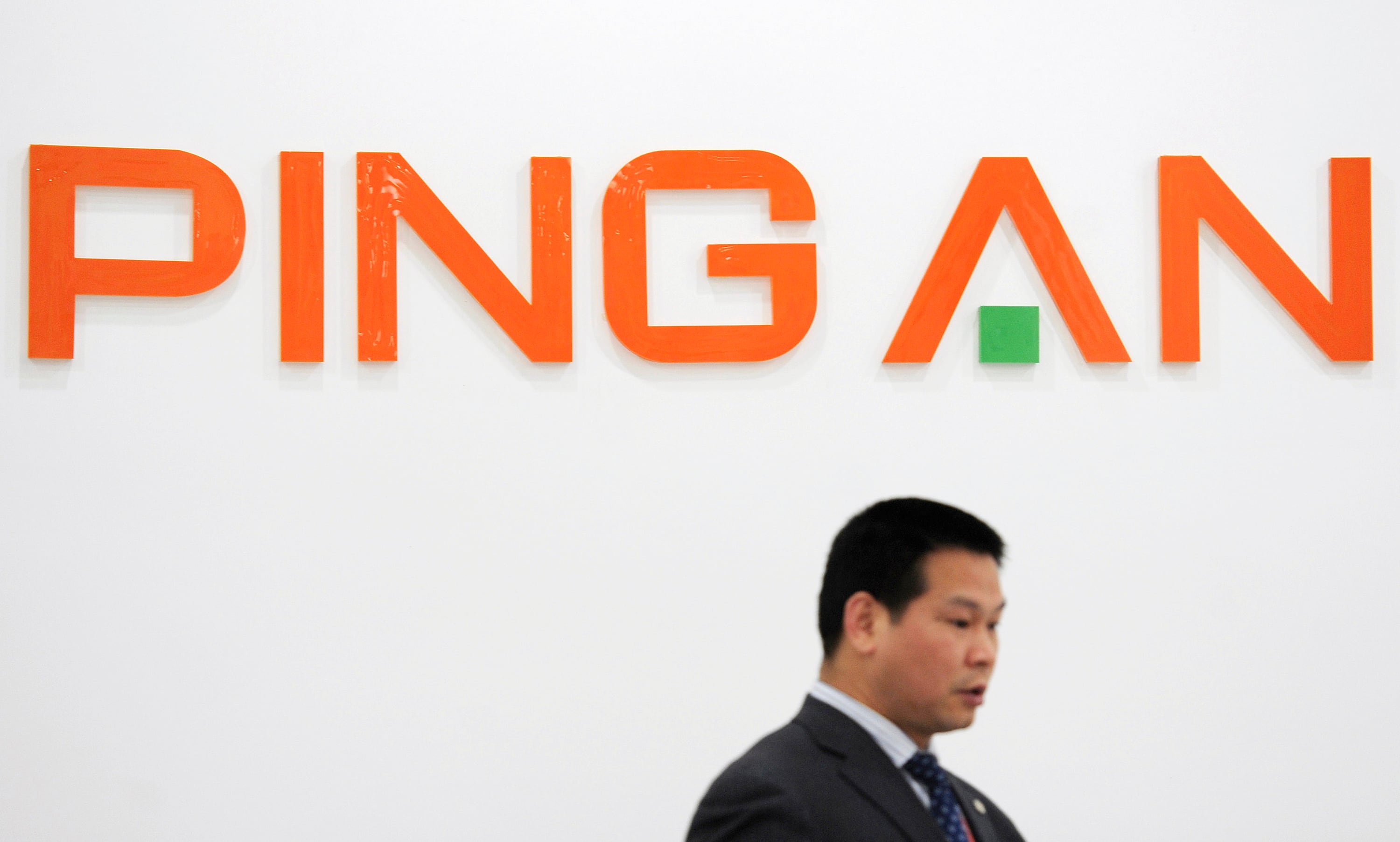 An employee walks past the company logo of Ping An Insurance at its branch in Hefei