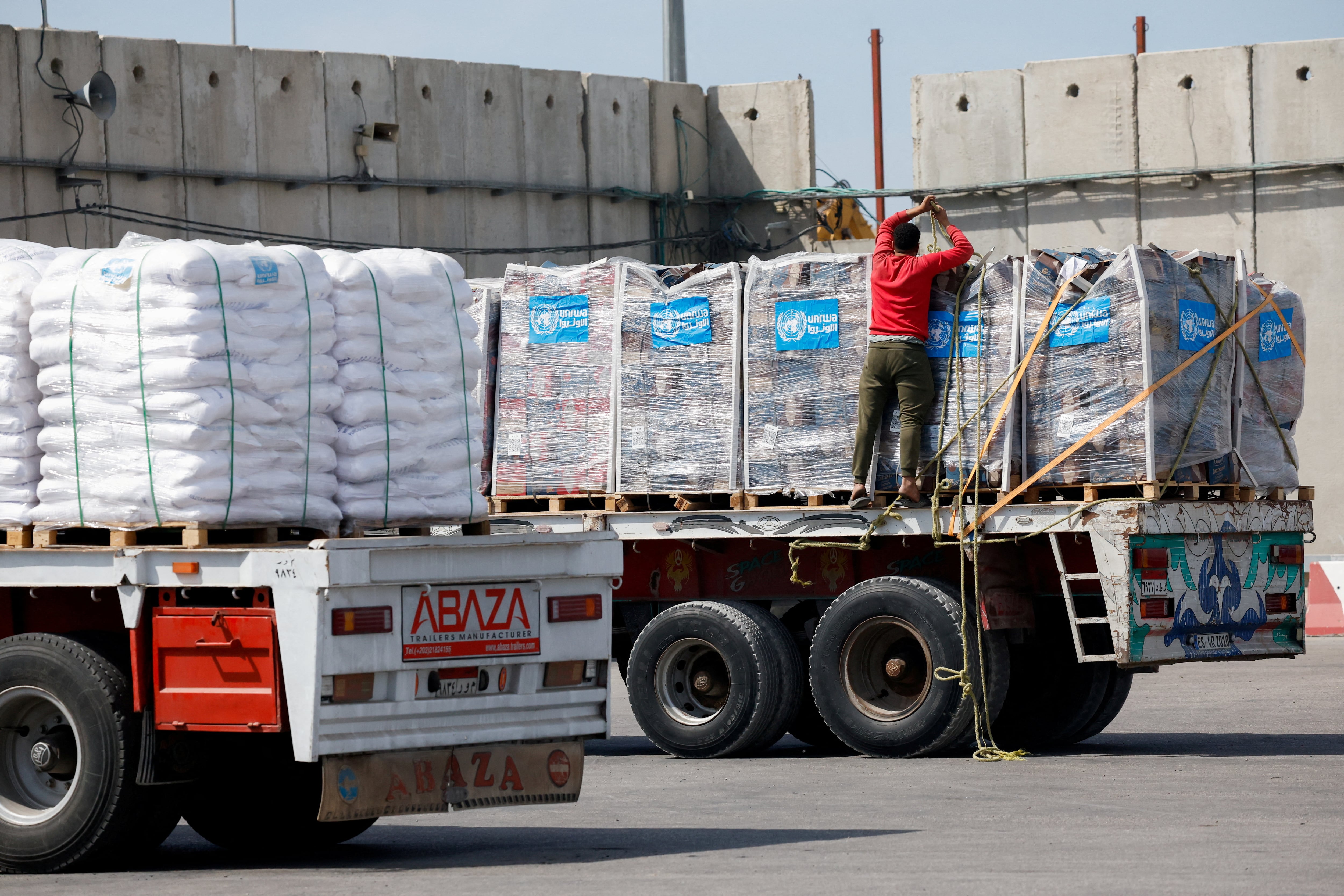 A driver adjusts a rope as he stands on a truck carrying humanitarian aid bound for the Gaza Strip at the Kerem Shalom crossing